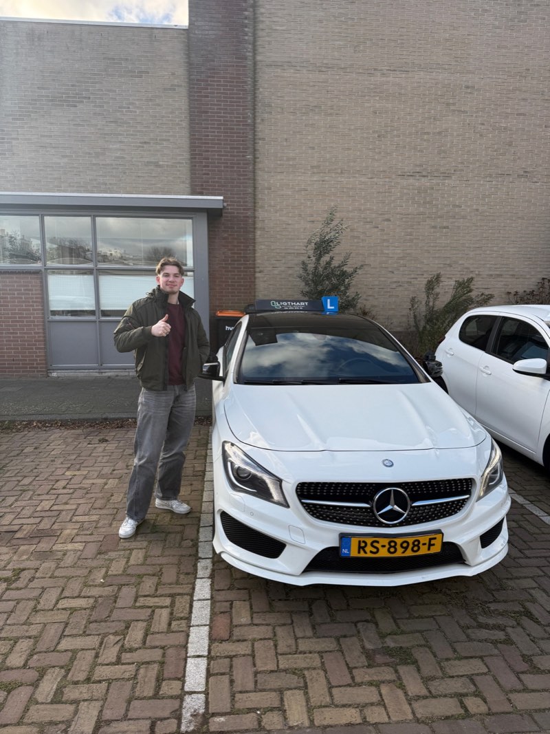 Geslaagde leerling naast de lesauto van Autorijschool Ligthart